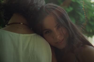 a woman with long hair hugging another woman