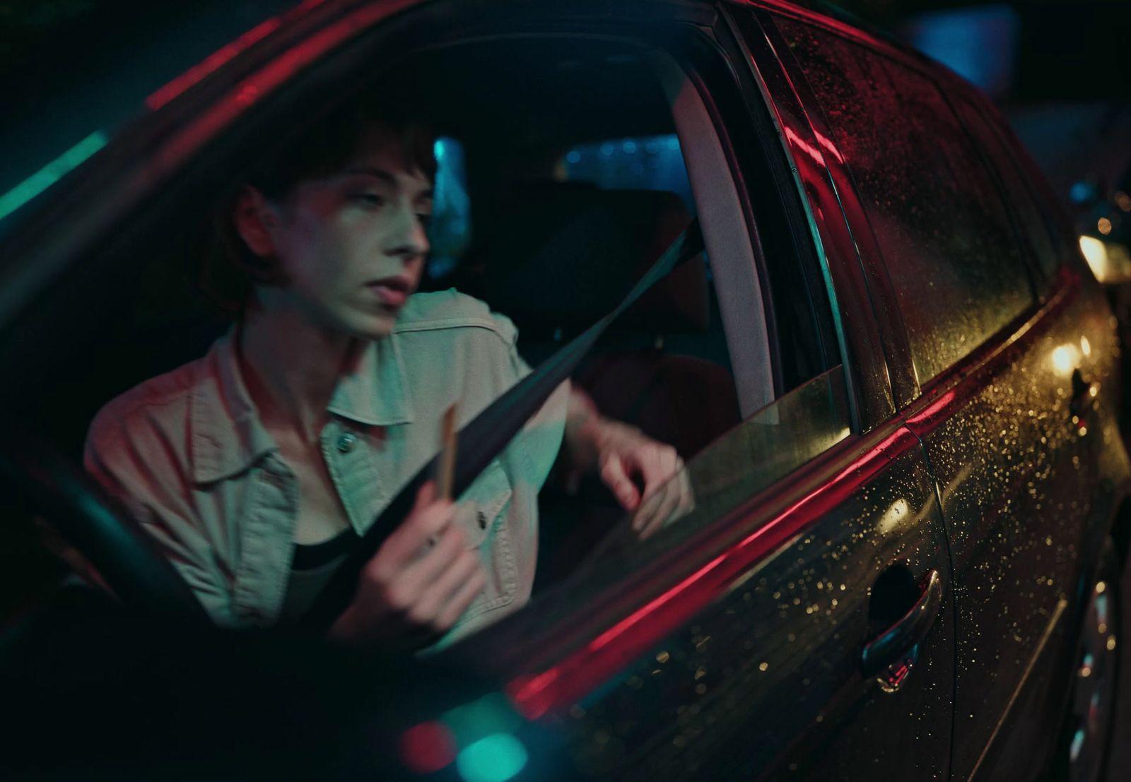 a woman sitting in a car with a knife in her hand