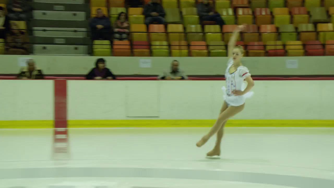 a woman in a white leotard skating on an ice rink