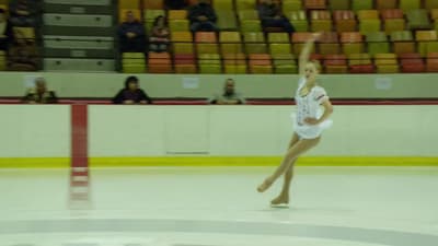 a woman in a white leotard skating on an ice rink