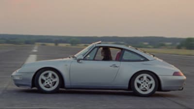 a silver car driving down a road next to a field