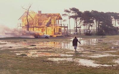 a person walking through a puddle in front of a house
