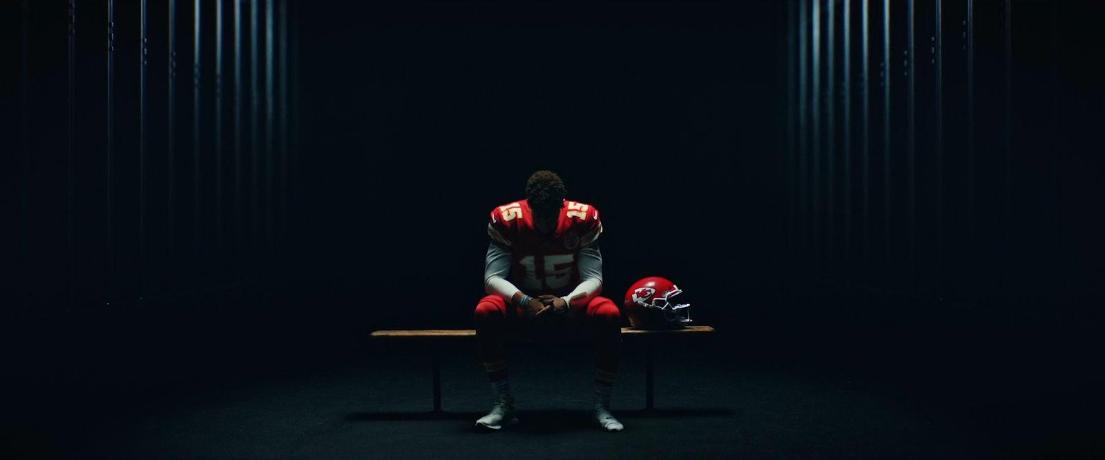 a football player sitting on a bench in the dark