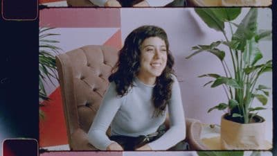a woman sitting in a chair next to a potted plant