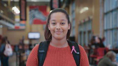 a girl with a pink ribbon on her backpack
