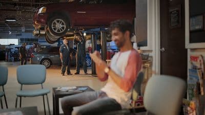 a man sitting on a chair in front of a car
