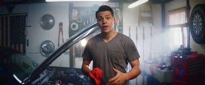 a man standing in a garage holding a wrench