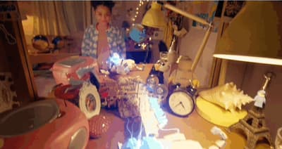 a woman standing next to a table filled with clocks