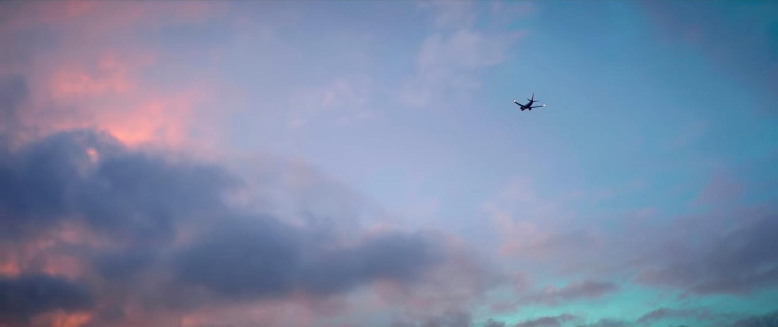 a plane flying through a cloudy blue sky