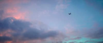 a plane flying through a cloudy blue sky