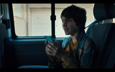 a young boy sitting in the back seat of a car looking at a cell phone