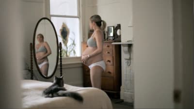 a pregnant woman standing in front of a mirror