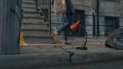 a person walking down a street next to a red lamp