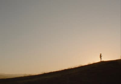 a person standing on top of a grass covered hill