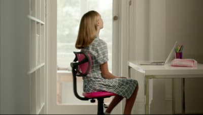 a little girl sitting at a desk with a laptop