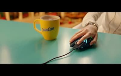 a woman's hand on a mouse next to a cup of coffee