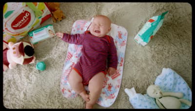 a baby laying on top of a blanket next to stuffed animals