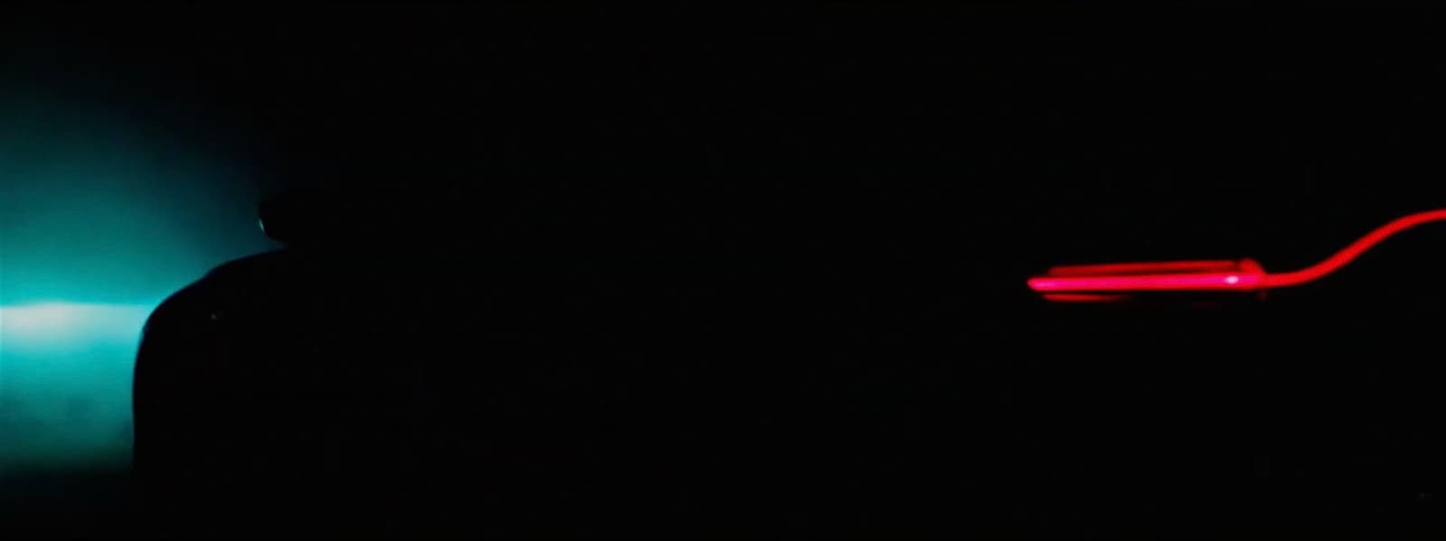 a person standing in the dark with a neon light