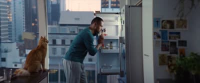 a man standing in front of a refrigerator next to a cat