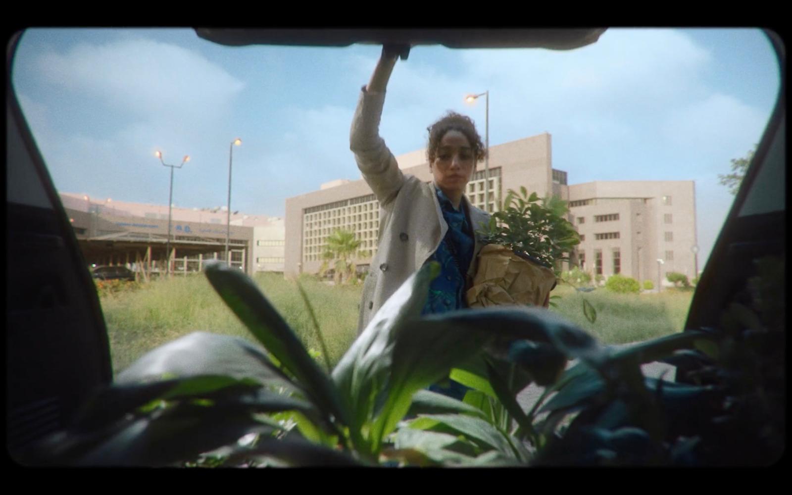 a woman holding a basket of plants in front of a building