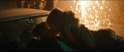 a man and a woman kissing in front of a car