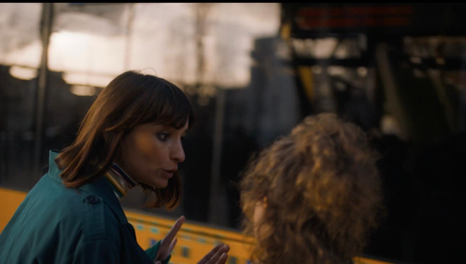 a woman standing next to another woman in front of a bus