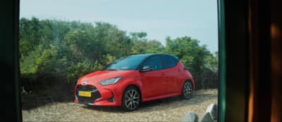 a red car is parked on a gravel road