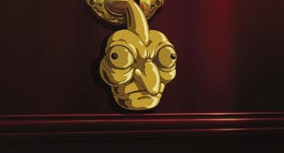 a golden mask hanging on a red wall