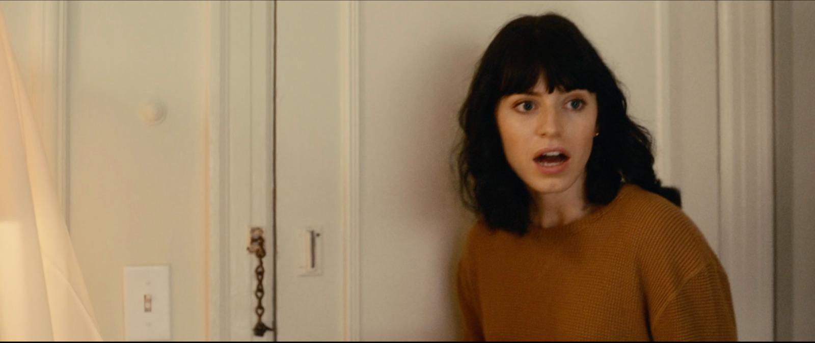 a woman standing in front of a door with a surprised look on her face