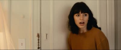 a woman standing in front of a door with a surprised look on her face