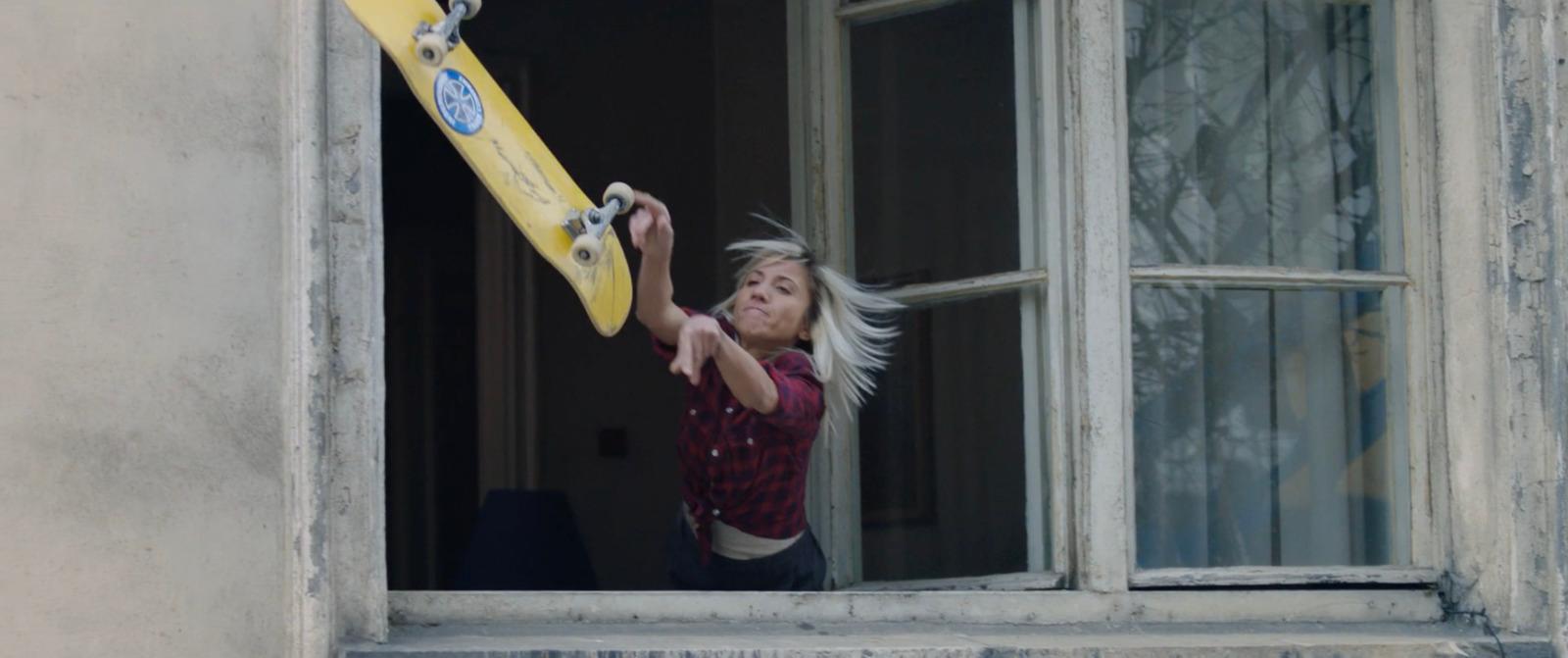 a woman holding a skateboard up to a window