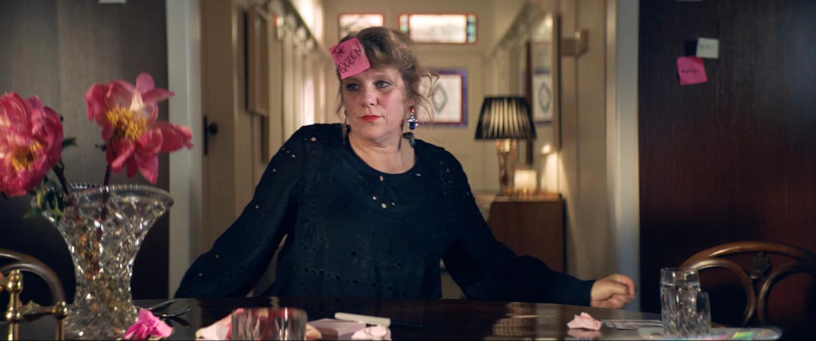 a woman sitting at a table with a pink flower in her hair