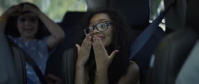 a woman sitting in the back of a car with her hands on her face