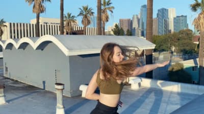 a woman with long hair standing on top of a roof