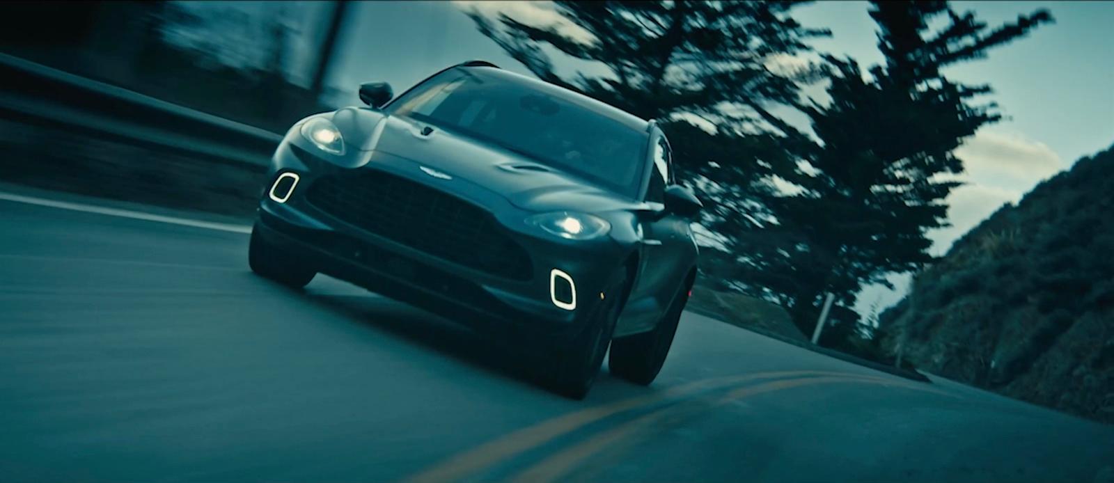 a black car driving down a road next to a forest