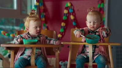 two young children sitting at a table eating