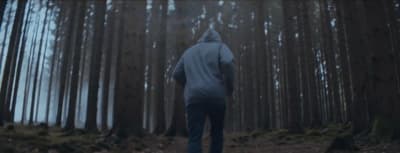 a person in a hooded jacket walking through a forest