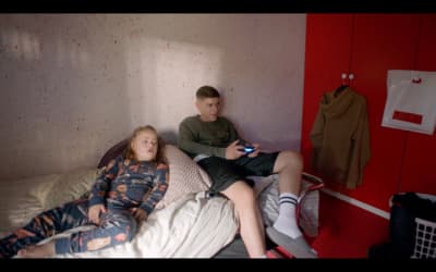 a boy and a girl sitting on a bed