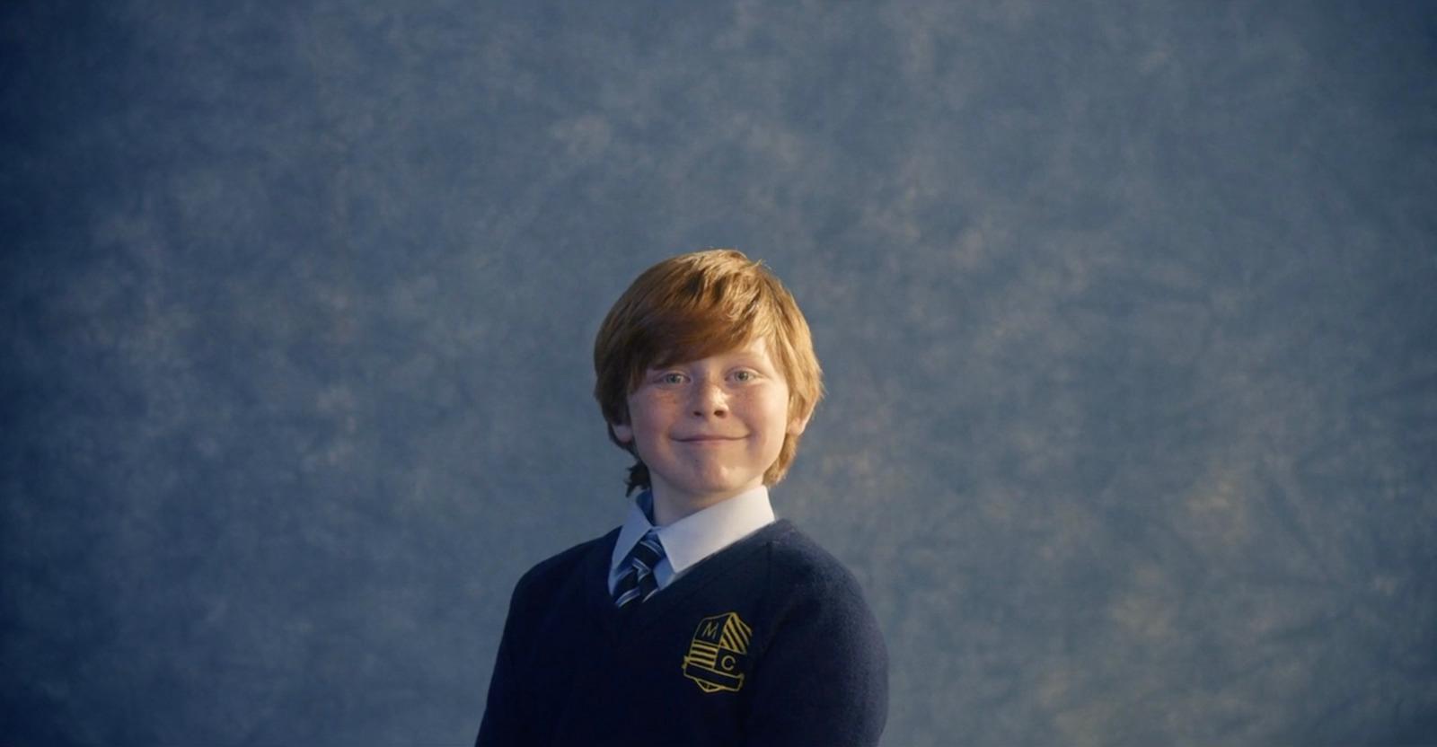 a young boy wearing a sweater and tie