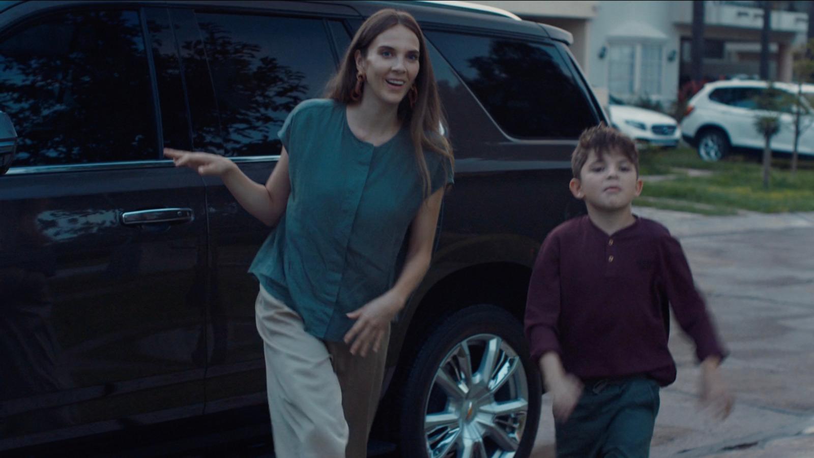 a woman standing next to a boy in front of a car