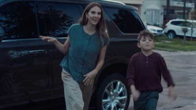 a woman standing next to a boy in front of a car