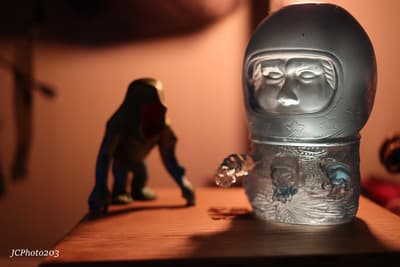 a glass bottle with a face on it next to a figurine