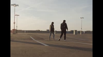 a couple of people walking across a parking lot
