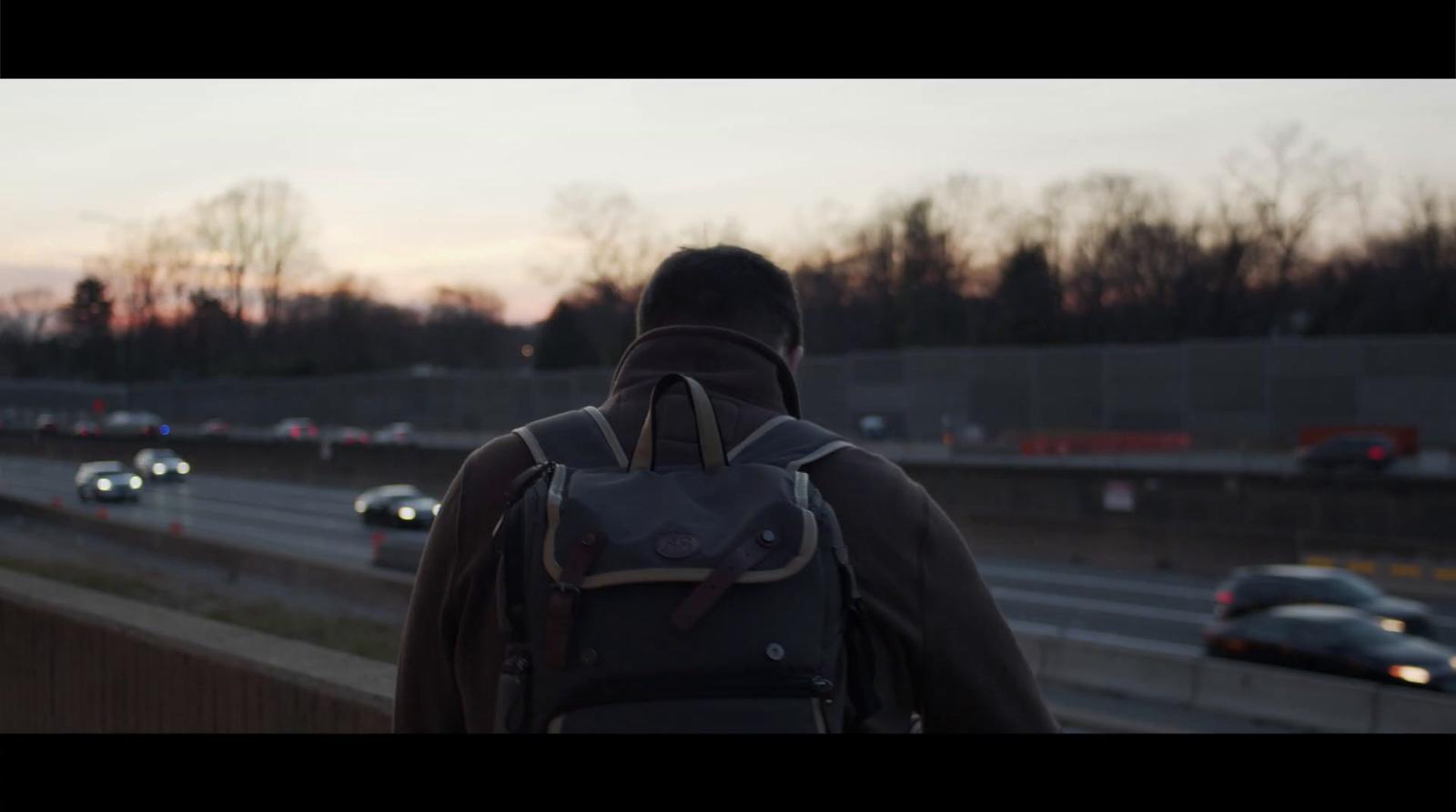 a man with a backpack walking down a highway