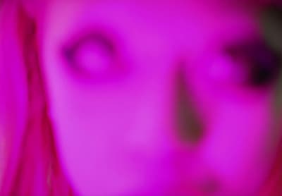 a blurry image of a woman's face with pink hair