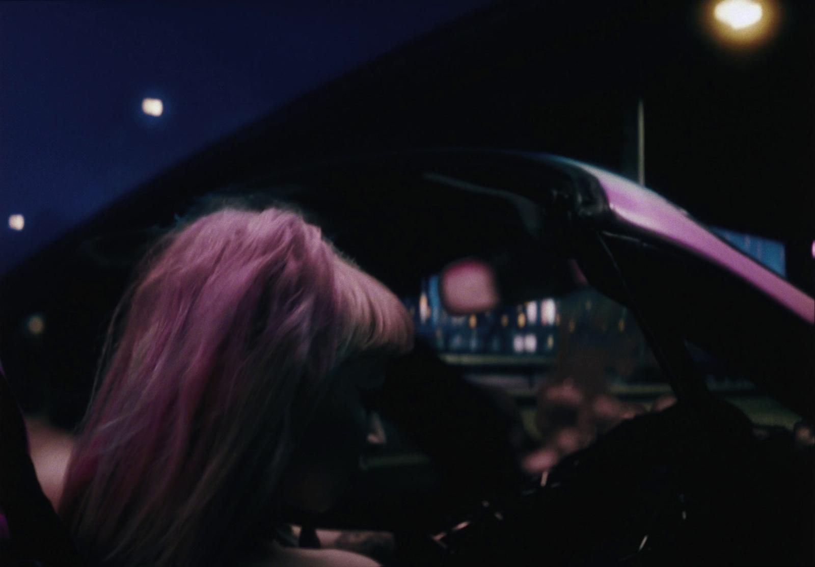 a woman with pink hair sitting in a car
