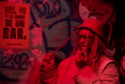 a man with dreadlocks standing in front of a graffiti covered wall