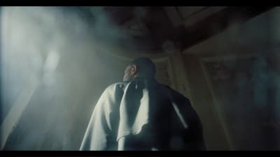 a man in a white cloak standing in a dark room