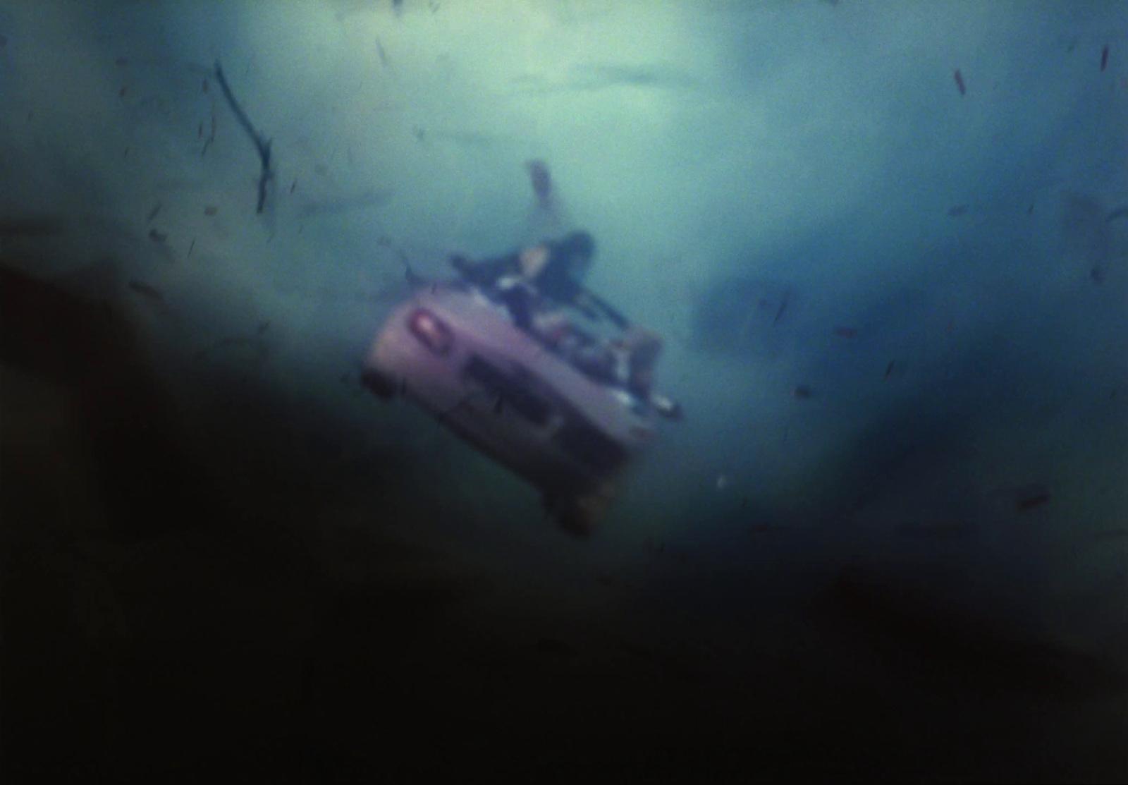 a man riding on the back of a pink car under water