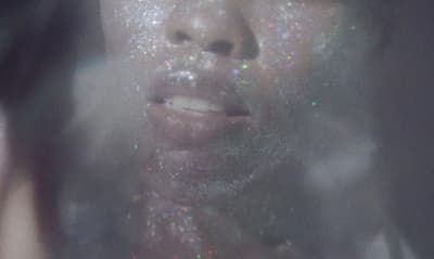 a woman with glitter on her face looking at the camera